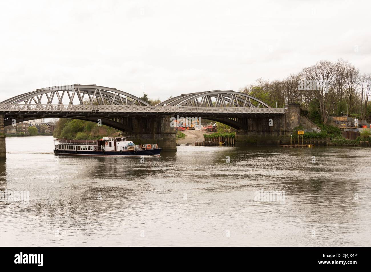 Un bateau de plaisance vide passant sous le pont Barnes sur la Tamise à Barnes, dans le sud-ouest de Londres, Angleterre, Royaume-Uni Banque D'Images