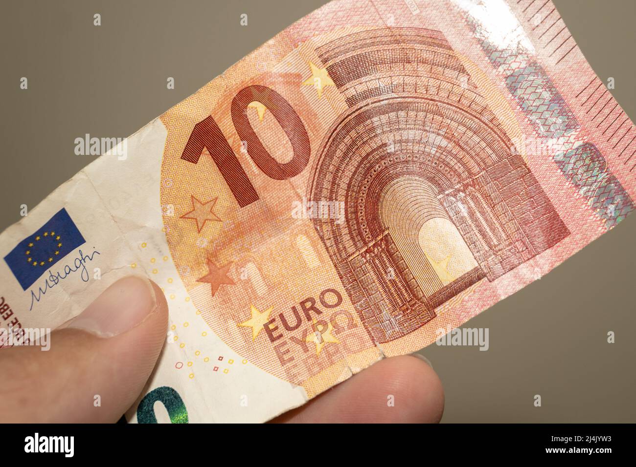 Personnes donnant la main de la monnaie de l'Angleterre au Royaume-Uni - un rouge dix (10) livre note sur un fond marron. Bureau de change. Banque D'Images