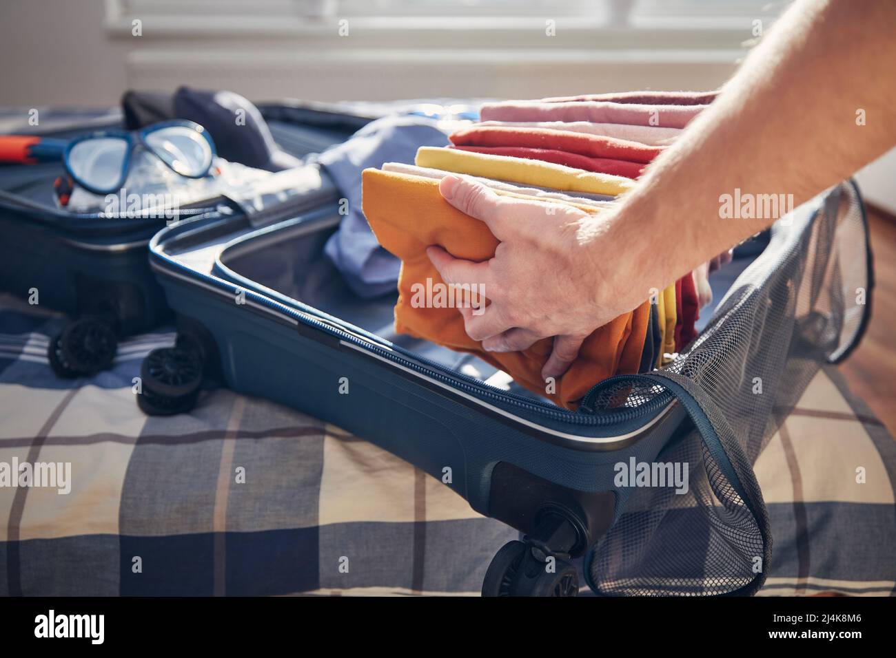 Valise ouverte avec vêtements d'été et lunettes de plongée sur le lit à la maison. Emballage et planification voyage aventure. Banque D'Images