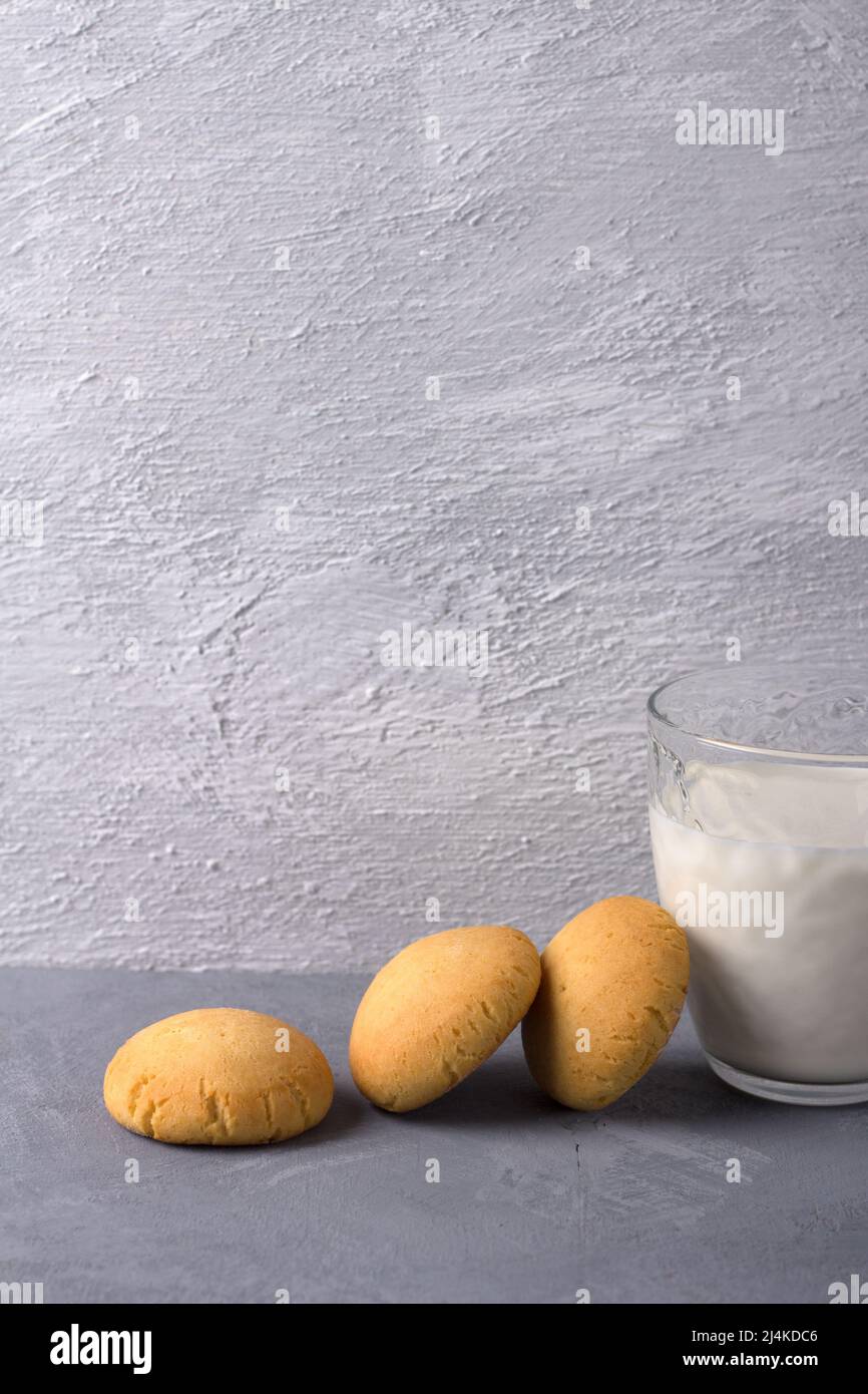 Petits gâteaux de riz faits maison au fromage cottage sans gluten et verre de lait sur fond texturé gris, sélectif. Nourriture saine et savoureuse Banque D'Images