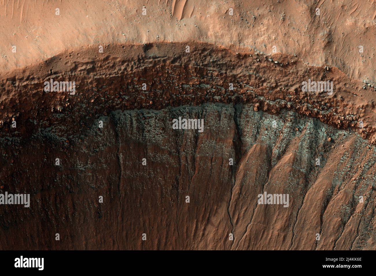 Washington, États-Unis. 16th avril 2022. La caméra HiRISE de l'Orbiter de reconnaissance Mars montre de petites parcelles de glace sèche près de l'équateur sur les pentes en pole position, qui sont plus froides parce qu'elles reçoivent moins de lumière du soleil. Cette image a été prise au milieu de l'hiver dans l'hémisphère Sud de Mars et montre un cratère près de 37 degrés de latitude sud. La pente orientée sud présente un gel brillant inégal, bleu de couleur rehaussée. Crédit NASA/UPI : UPI/Alay Live News Banque D'Images