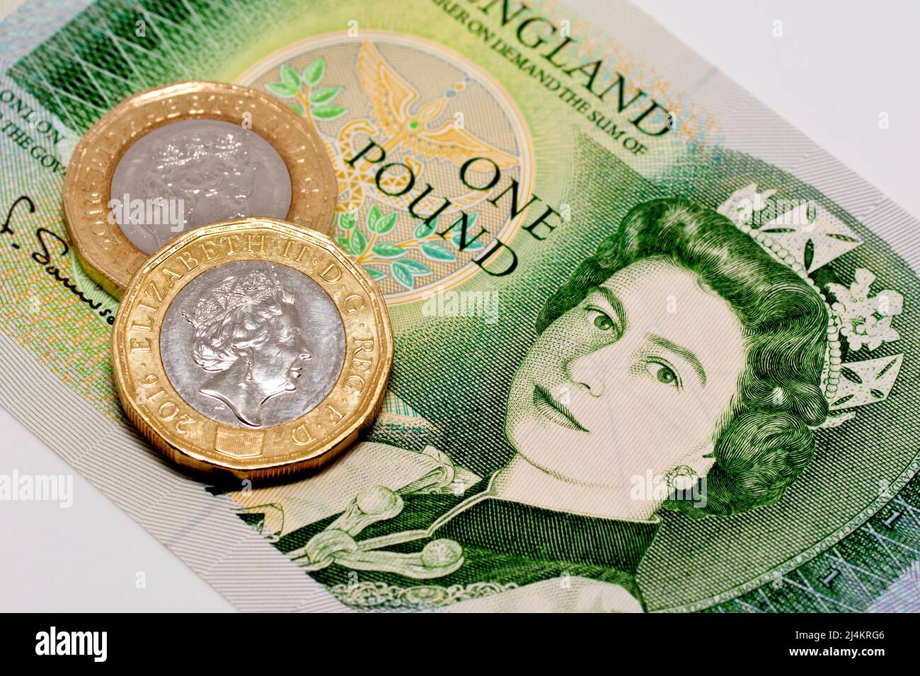 Gros plan de deux pièces de 1 livres sterling modernes, sur une note de 1 livres abandonnée et non plus légale. Banque D'Images