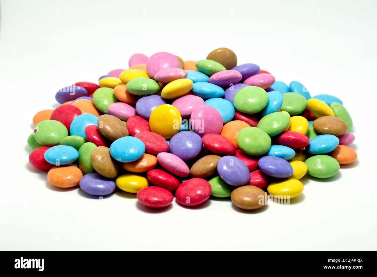 Gros plan sur une pile de friandises au chocolat multicolores et aux motifs croustillants, isolées sur un fond blanc. Banque D'Images