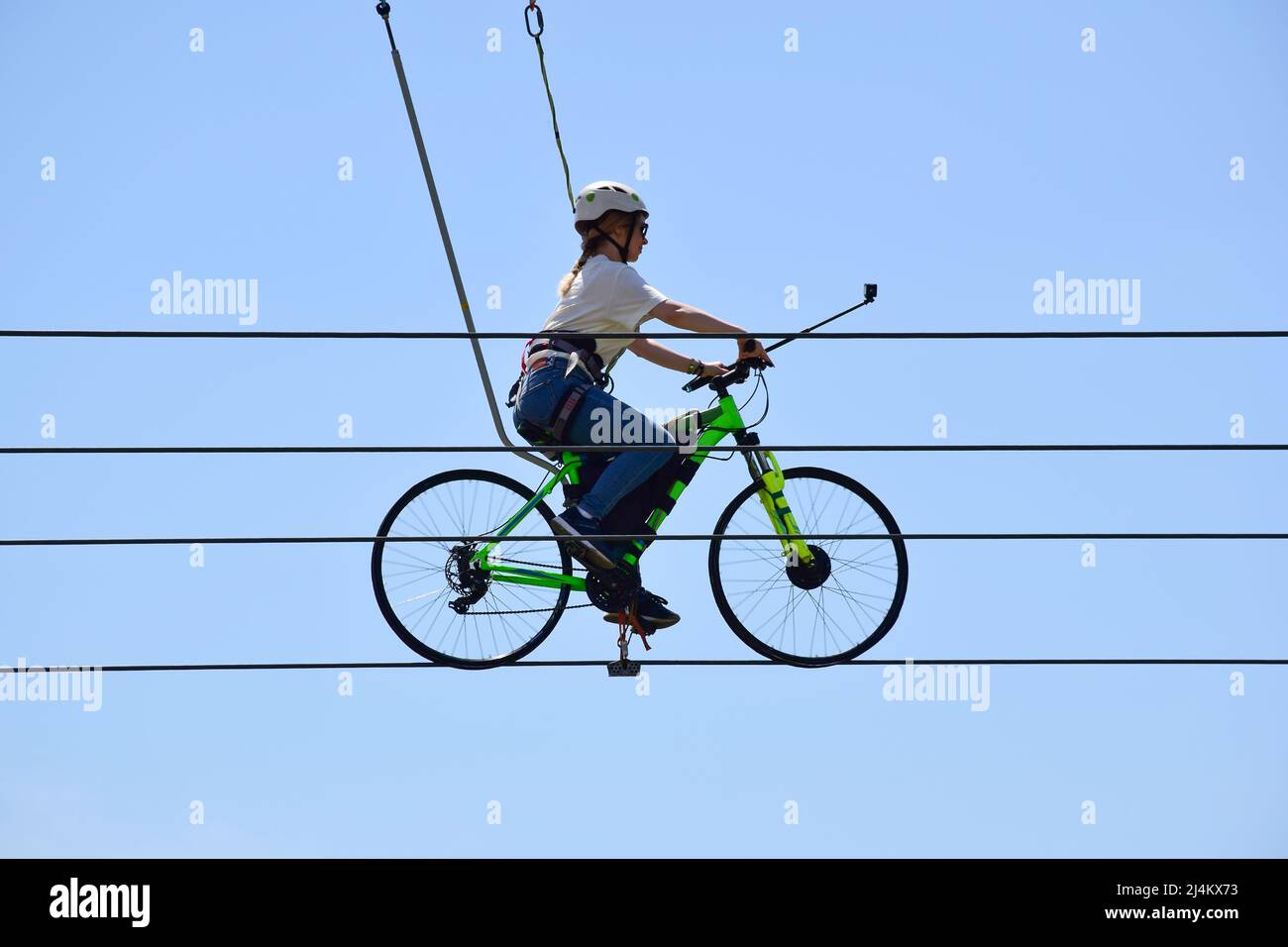Une jeune femme fait une balade à vélo sur des cordes au-dessus du sol. Contre le ciel bleu Banque D'Images