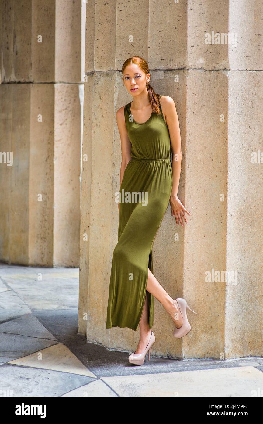 Habillez vous dans une robe longue sans manches verte talons hauts creme courbure d une jambe mains touchant le mur une jeune fille noire mode est debout pres d une colonne Photo Stock Alamy