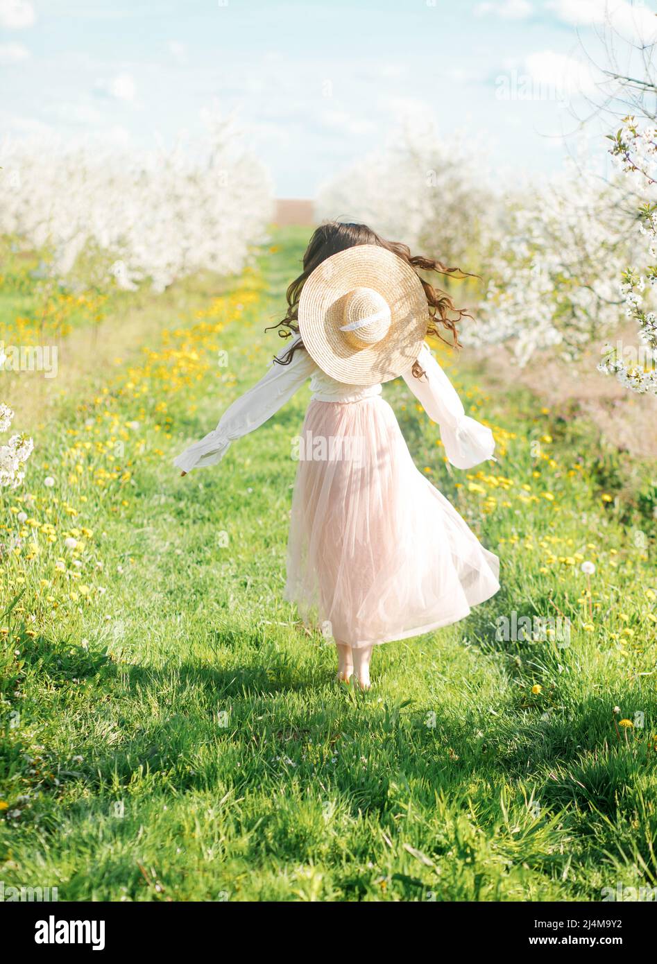 Portrait de printemps d'une belle fille dans une robe étonnante appréciant le printemps dans un jardin fleuri frais lors d'une journée ensoleillée. Banque D'Images