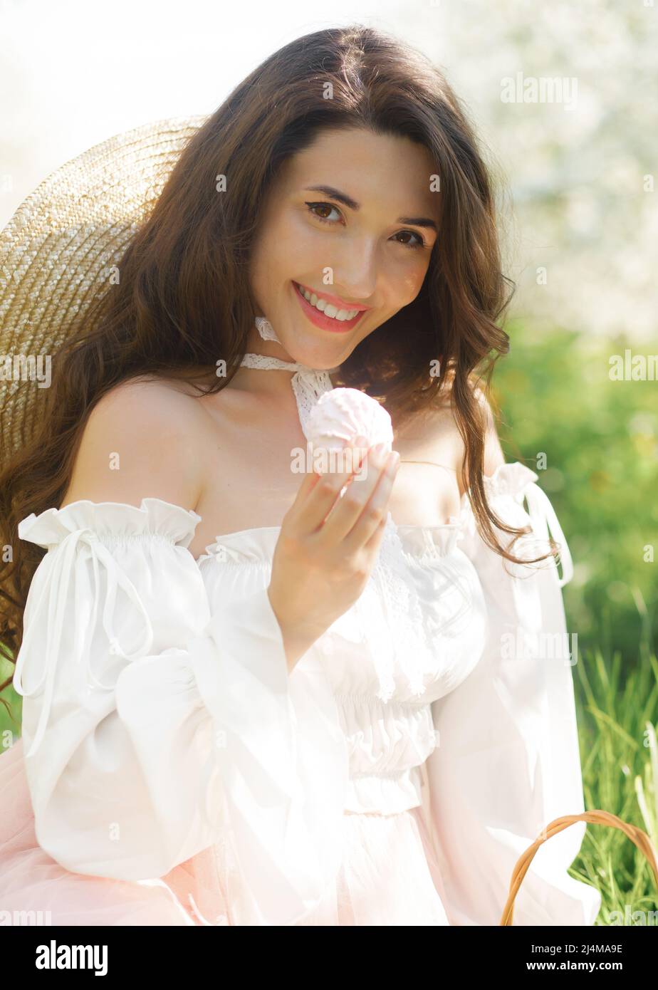 Portrait de printemps d'une belle fille dans une robe étonnante appréciant le printemps dans un jardin fleuri frais lors d'une journée ensoleillée. Banque D'Images