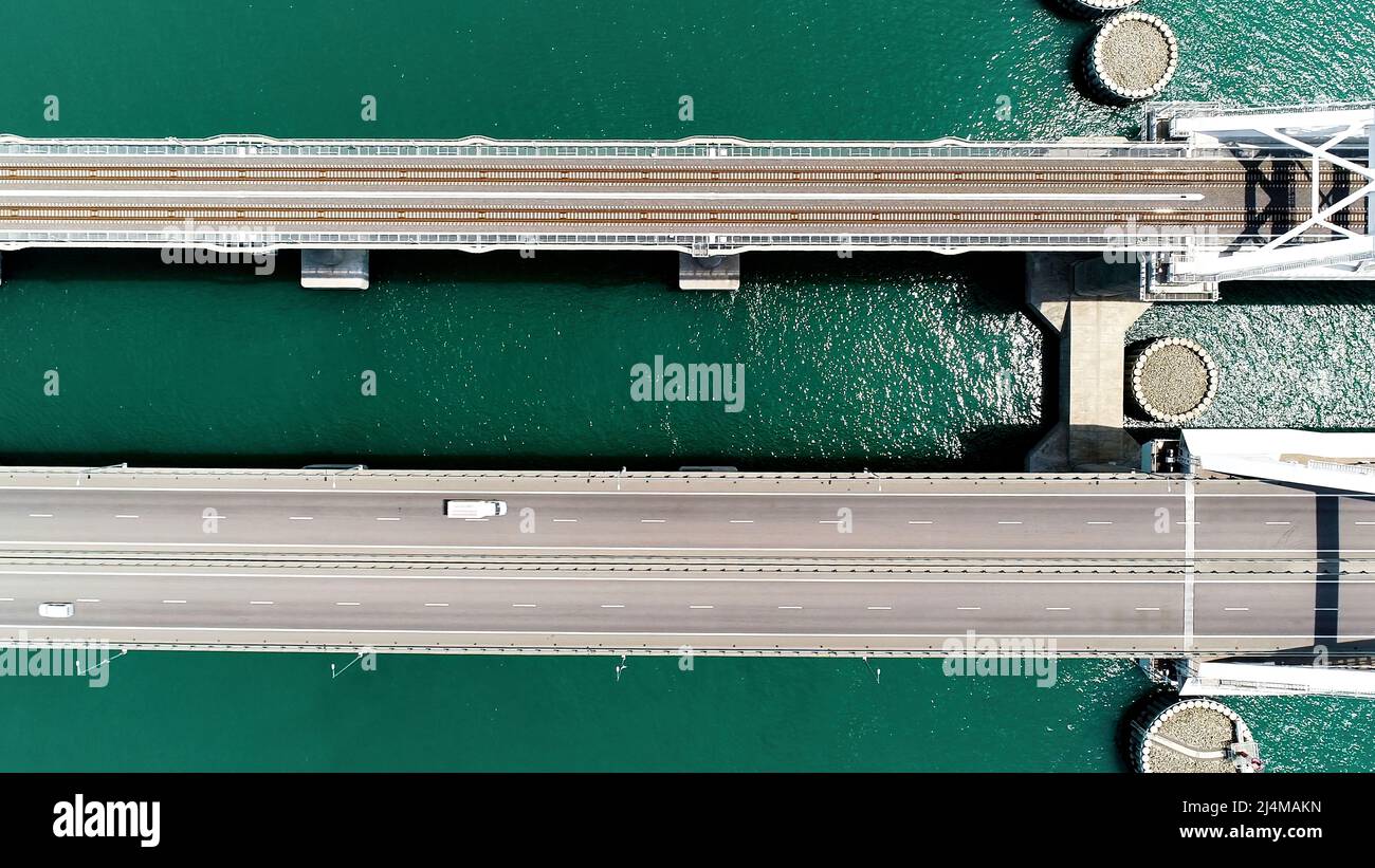 Vue d'été depuis un hélicoptère. Action. Un énorme pont pour déplacer des voitures fait haut au-dessus de la mer et le ciel bleu de jour. Banque D'Images