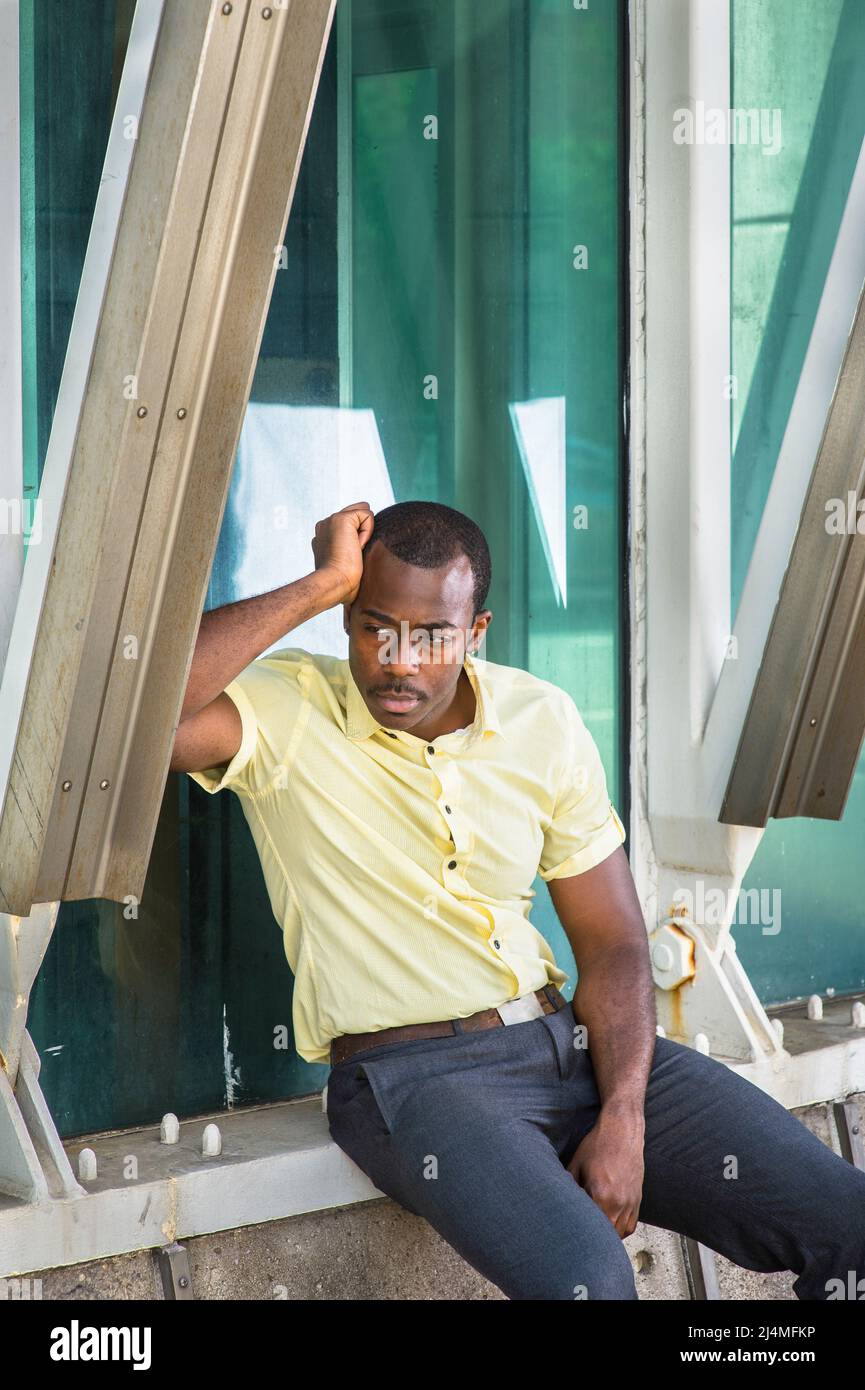 Dans une chemise jaune clair, un pantalon gris, un jeune homme noir  attrayant est debout par une structure, pensant à l'extérieur Photo Stock -  Alamy