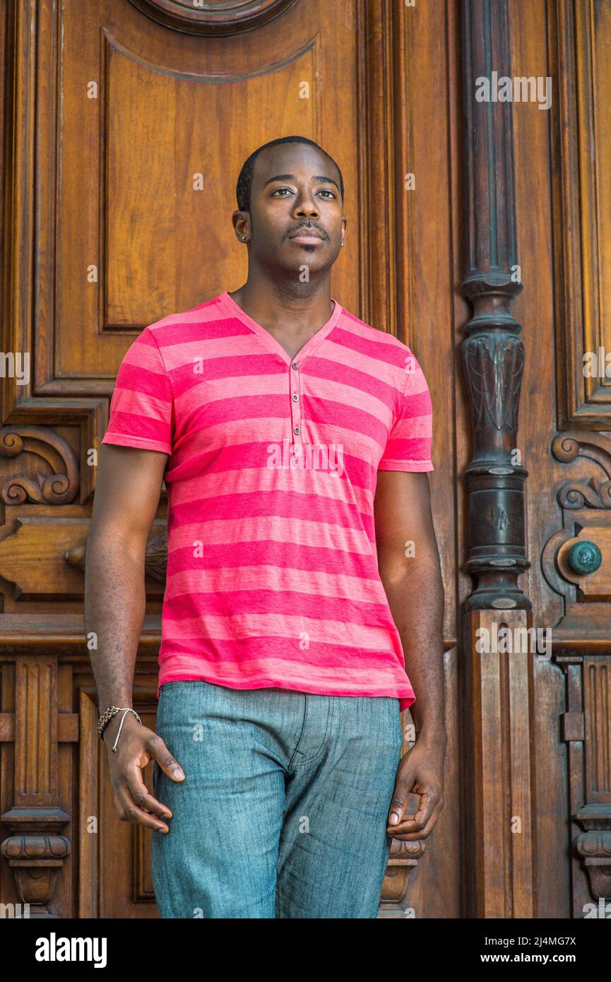 Portant une chemise a col en V Henley rouge et rose un pantalon gris un bracelet un jeune homme noir elegant avec une petite moustache se tient devant Photo Stock Alamy
