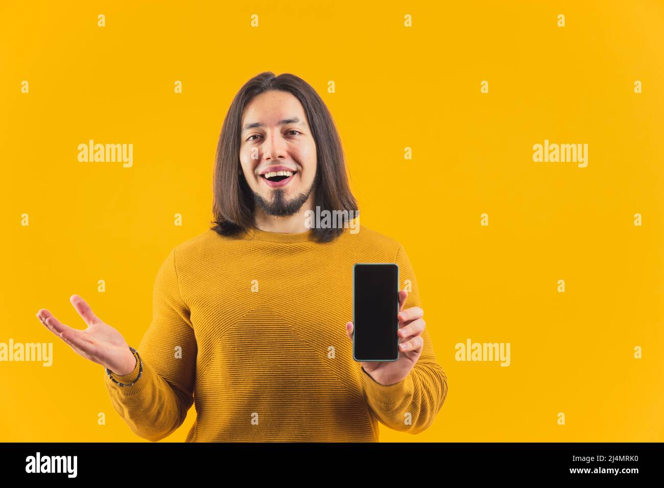 Jeune homme excité montrant écran noir de smartphone à la caméra et gardant une autre main ouverte ADS et promotion concept copie espace jaune arrière-plan studio tourné isolé . Photo de haute qualité Banque D'Images