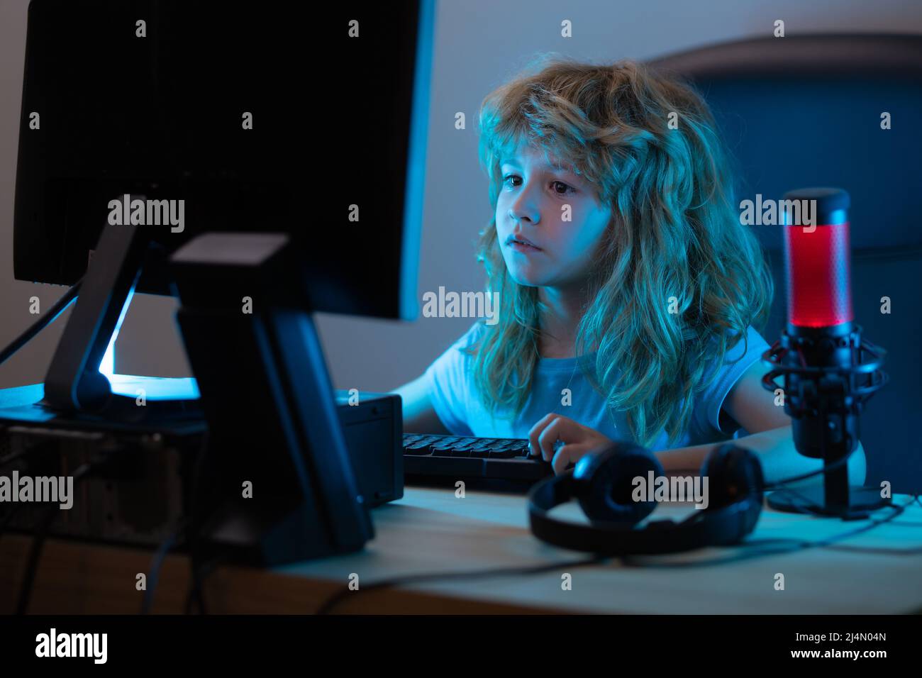 Petit garçon à l'écran de l'ordinateur de pc. Un enfant d'âge préscolaire  mignon regarde un film sur son bureau avant de dormir. Portrait d'un enfant  mignon tout en tapant sur le clavier