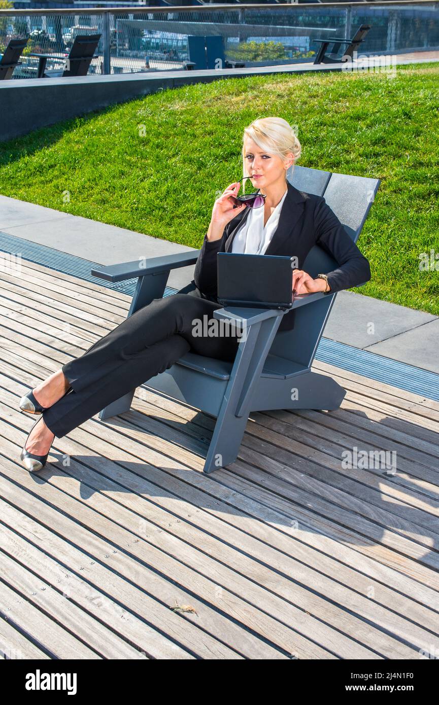 Vêtue de sous-vêtements blancs et d'un costume noir, tenant des lunettes de  soleil, croisant les jambes, une jeune femme d'affaires est assise sur une  chaise et travaille dessus Photo Stock - Alamy