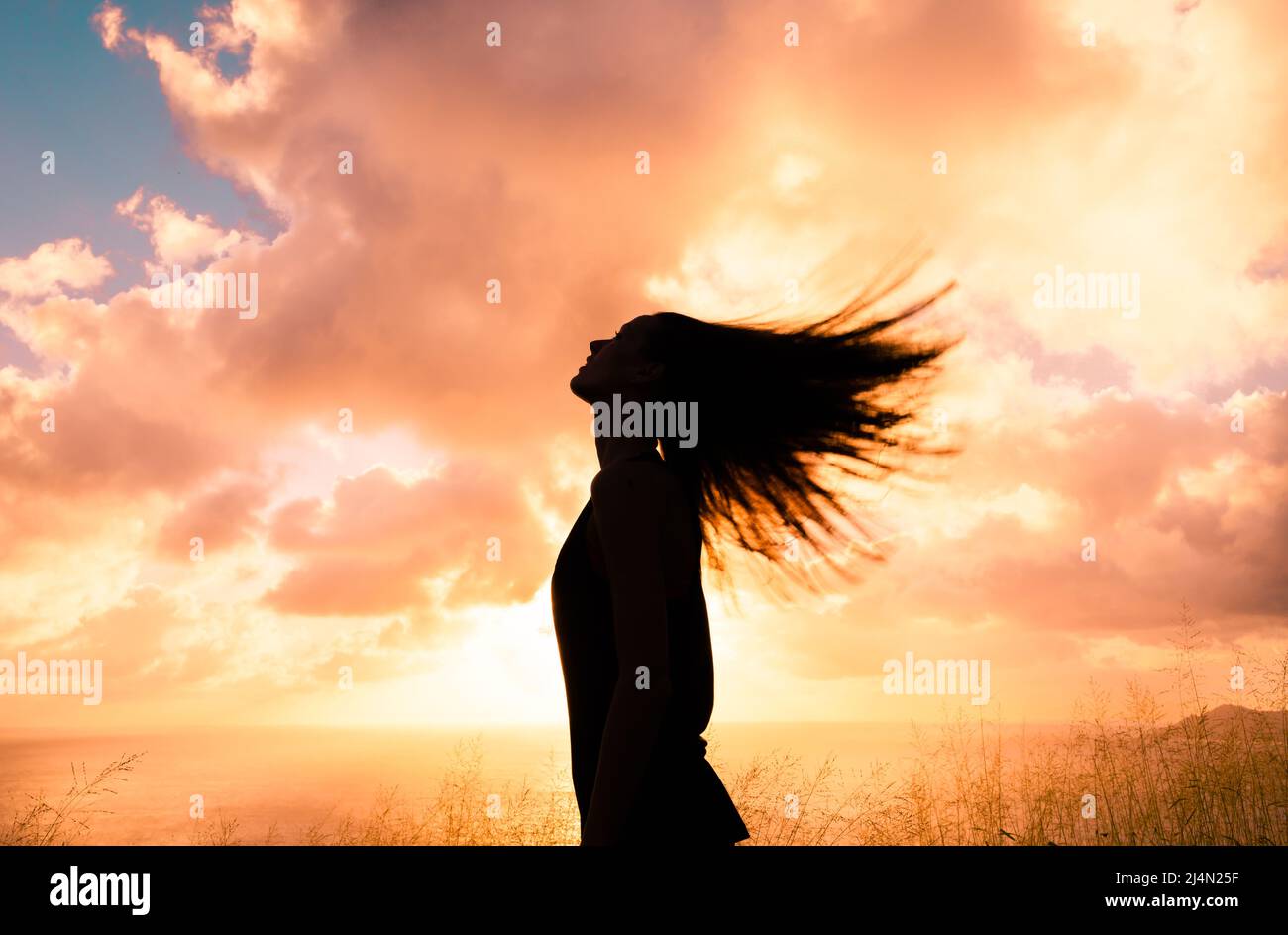 Femme regardant le coucher du soleil se sentant libre heureux Banque D'Images