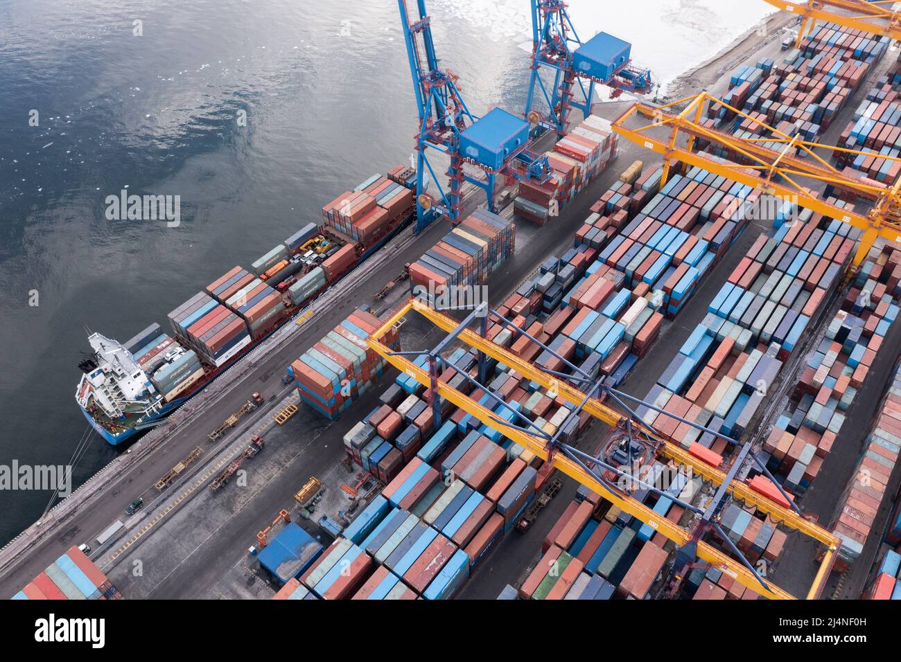 Vladivostok, Russie - 28 janvier 2022 : Vue de dessus du terminal des conteneurs du port maritime. En hiver, un bateau à conteneurs est en train de charger au quai. Banque D'Images