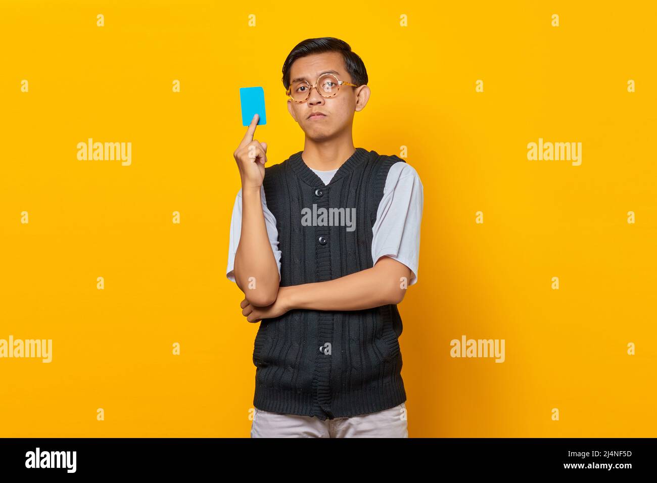 Portrait d'un jeune asiatique choqué montrant une carte de crédit sur fond jaune Banque D'Images