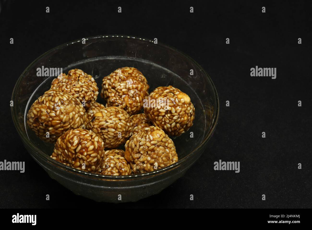 Les boules de sésame sont dans une tasse. Sur fond noir Banque D'Images
