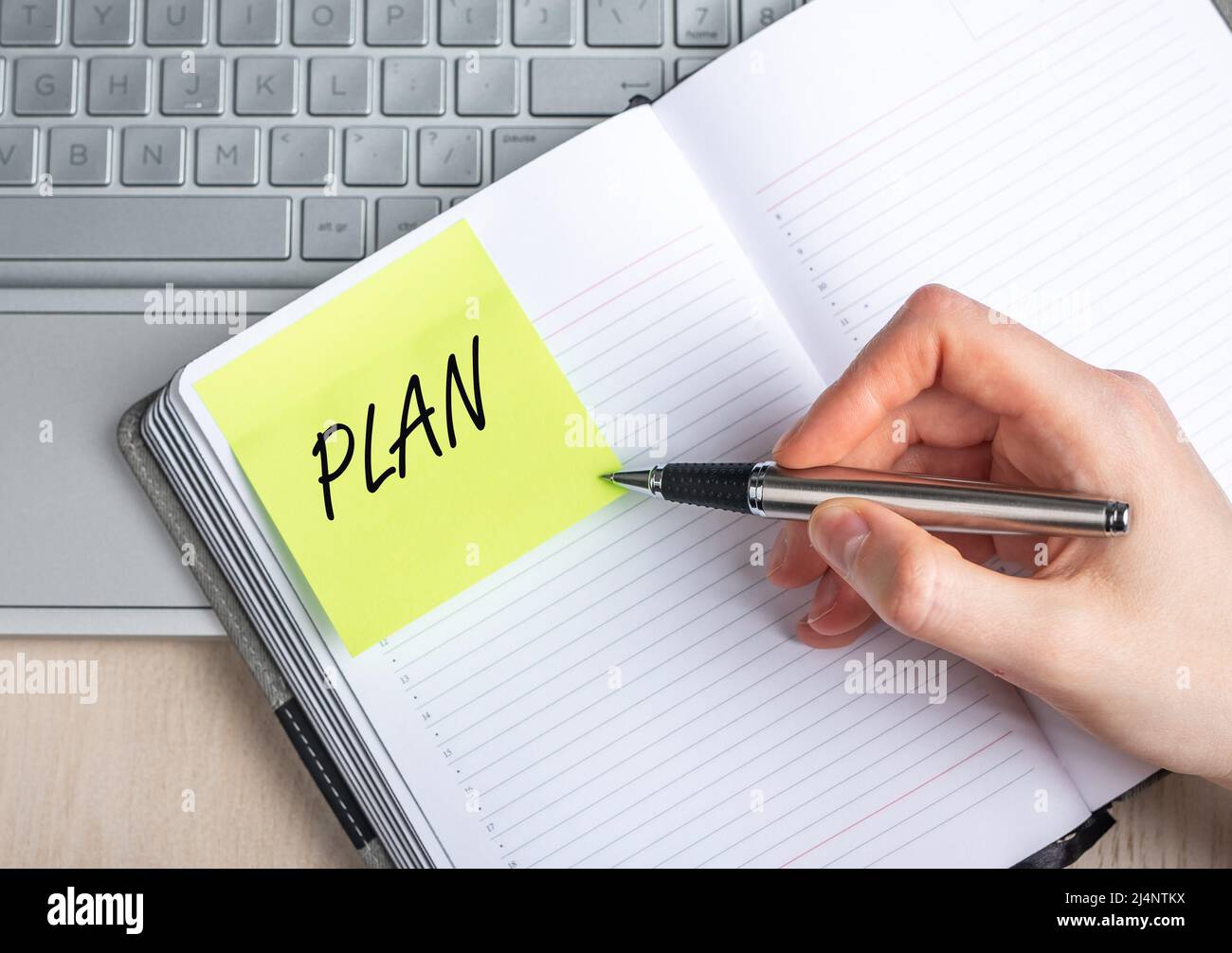 Femme gros plan à la main écrivant des plans dans le bloc-notes. Gestion du temps, concept d'organisation. Femme assise à table avec ordinateur portable et prenant des notes. Photo de haute qualité Banque D'Images