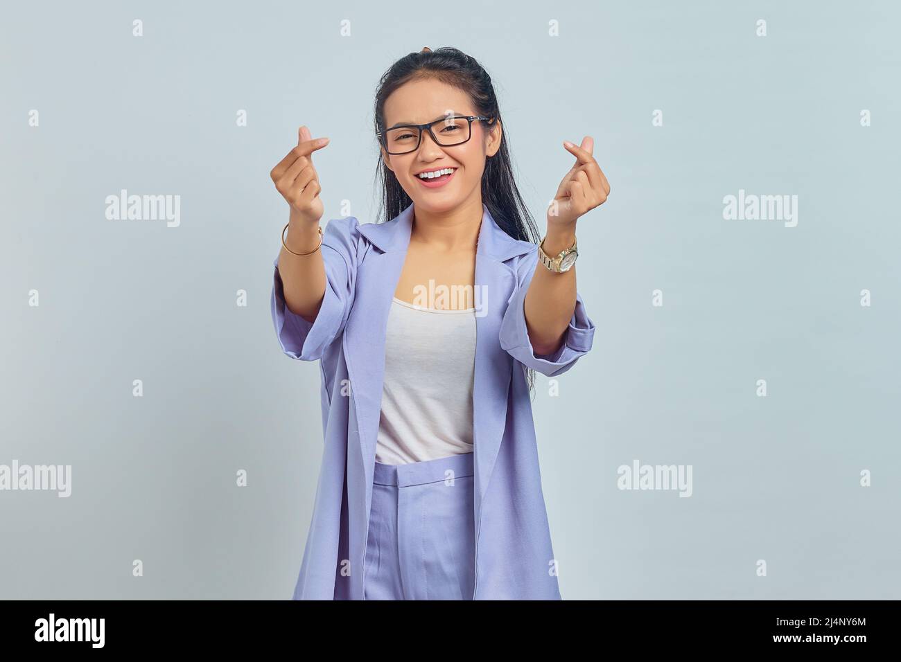 Portrait d'une jeune femme asiatique souriante montrant le cœur coréen avec deux doigts croisés, exprimer la joie et la positivité isolées sur fond blanc Banque D'Images