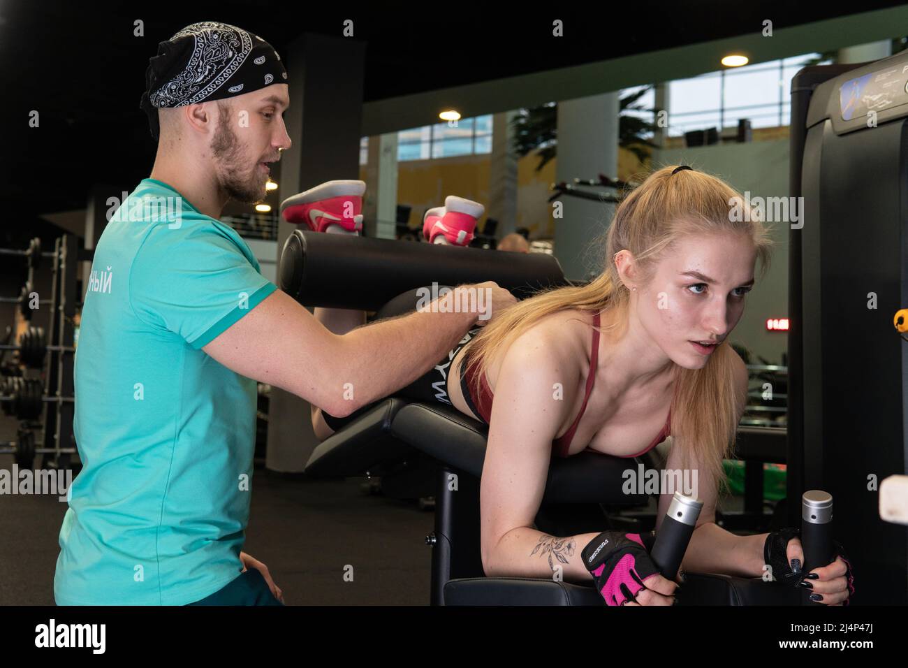 L'entraînement dirigé par un instructeur aide un beau client à effectuer des exercices dans un club de remise en forme, le concept de jouer du sport avec un loisir professionnel de gym Banque D'Images