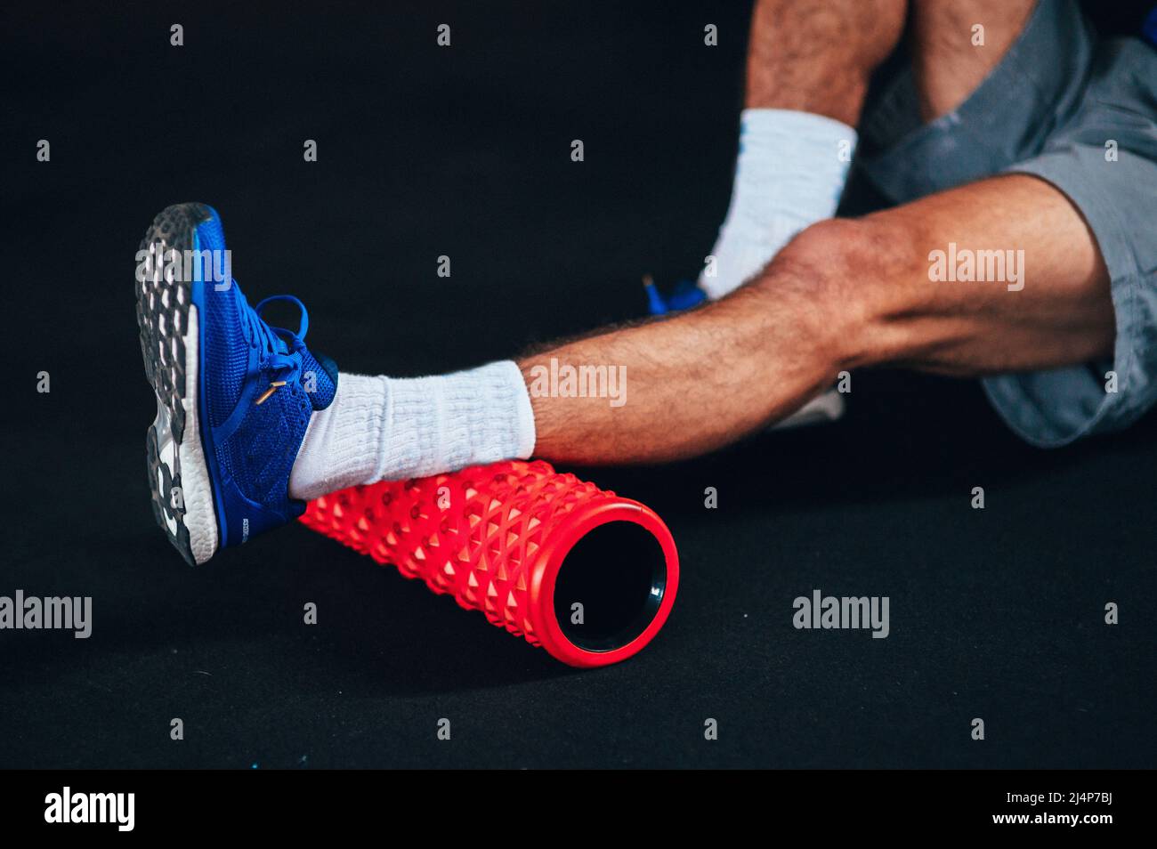 Une jambe d'athlète qui se réchauffe et se réchauffe avec un rouleau en  mousse. Arrière-plan sombre et équipement sportif rouge. Photo contrastée,  préchauffage et fonctionnalité Photo Stock - Alamy