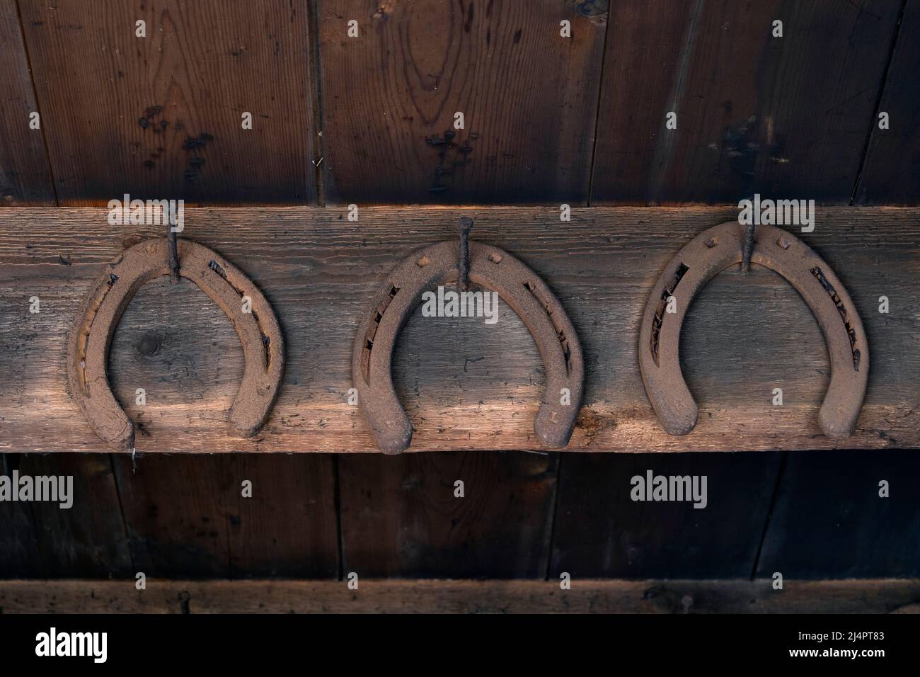 D'anciennes fers à cheval rouillés d'époque accrochés au mur dans une grange comme symbole de chance Banque D'Images