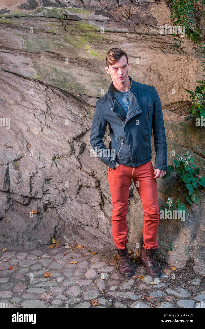 Vêtu d'une veste coupe slim bleue, d'un Jean rouge, d'une chaussure en cuir  marron, un jeune homme est debout près d'un mur rocheux, patiemment attendu  Photo Stock - Alamy