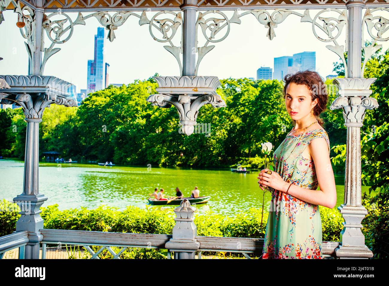 La jeune dame vous attend. Jolie jeune fille portant sans manches, longue robe, debout dans le pavillon au parc, main tenant la rose blanche, regardant Banque D'Images