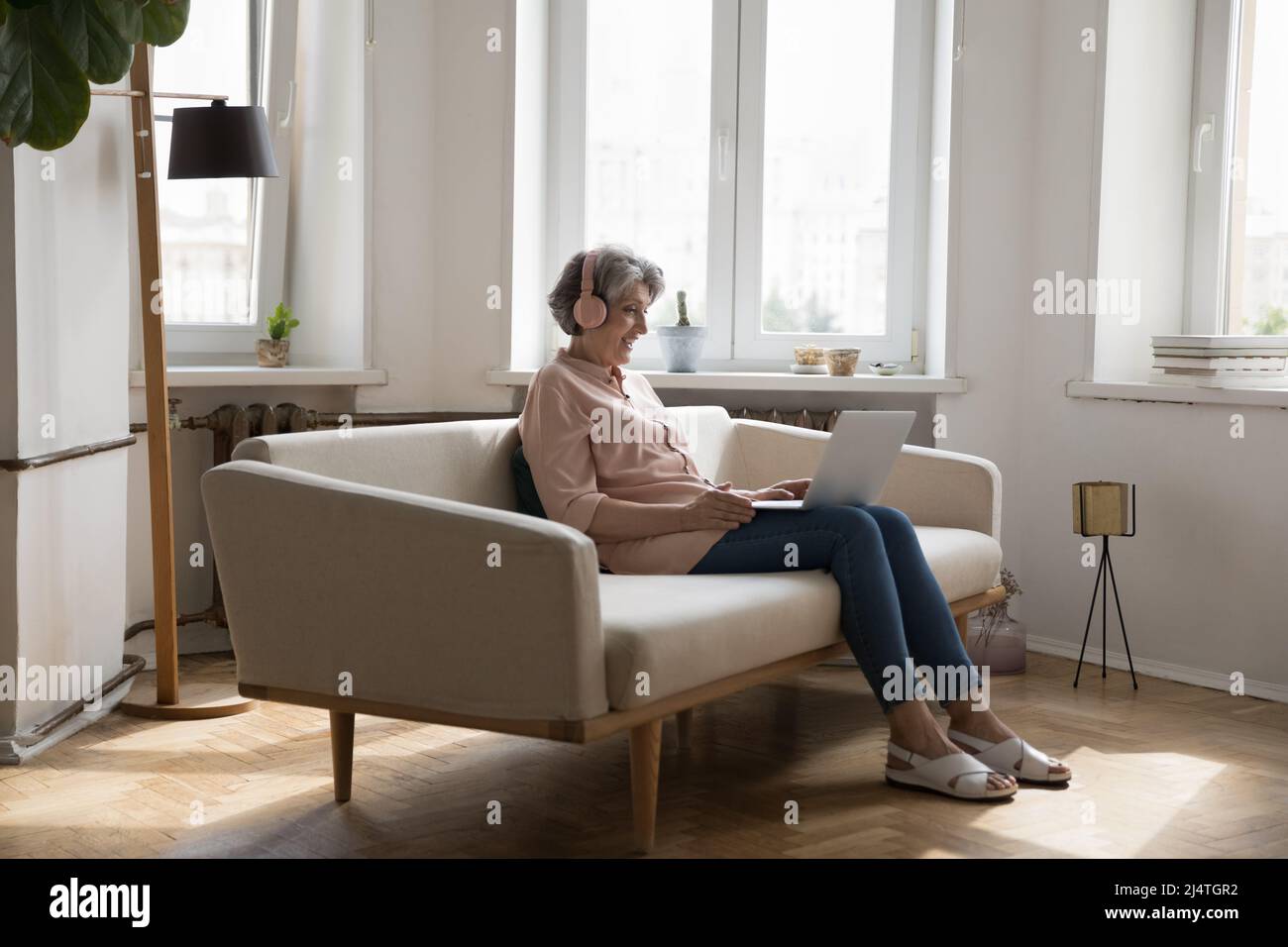 Une femme plus âgée porte un casque qui se fixe sur un ordinateur portable pour passer un appel vidéo Banque D'Images