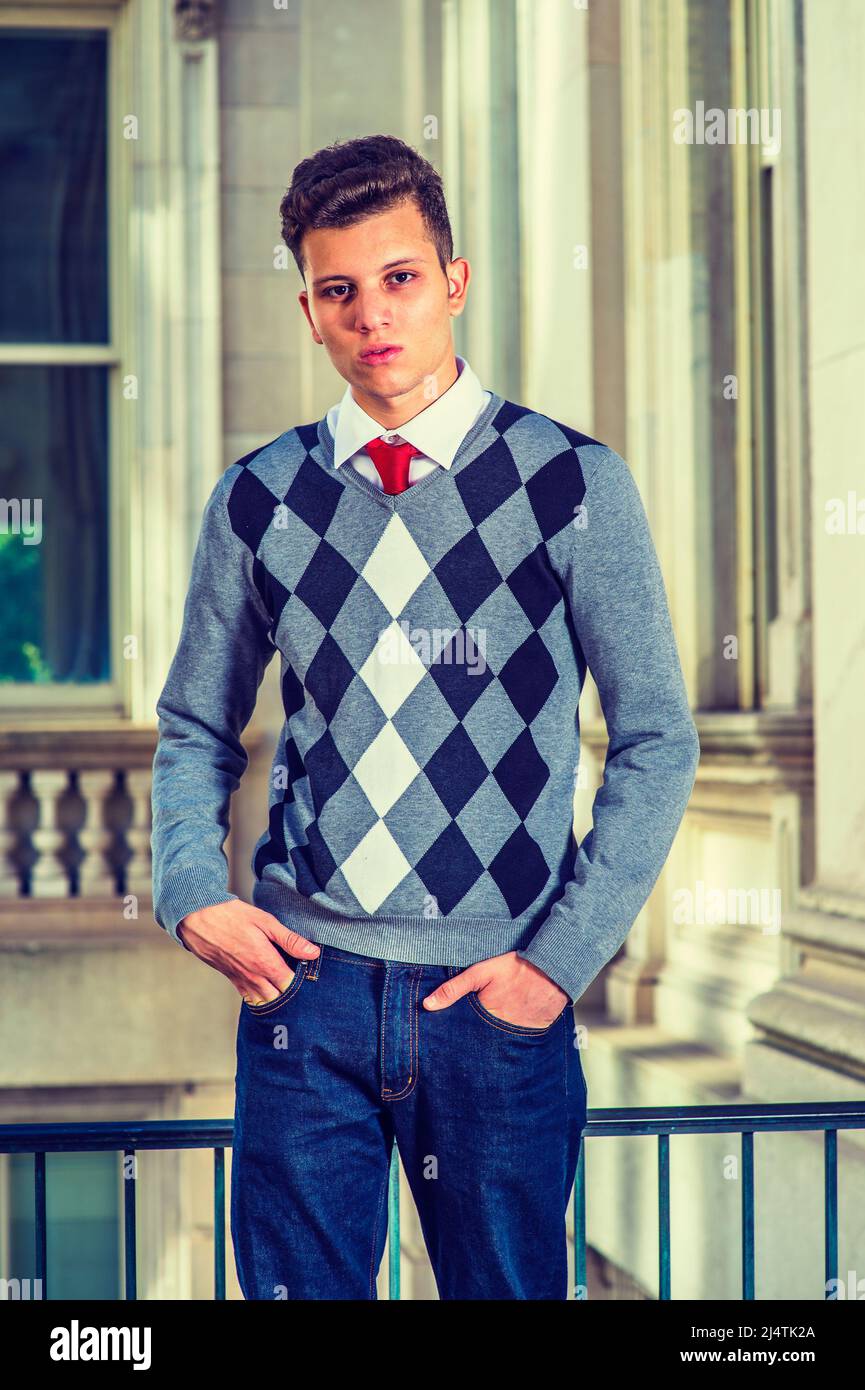 Portrait de l'étudiant de collège. Robe dans un pull à motifs noir, blanc, gris, jeans, mains dans les poches, un jeune homme d'affaires charmant est à côté Banque D'Images