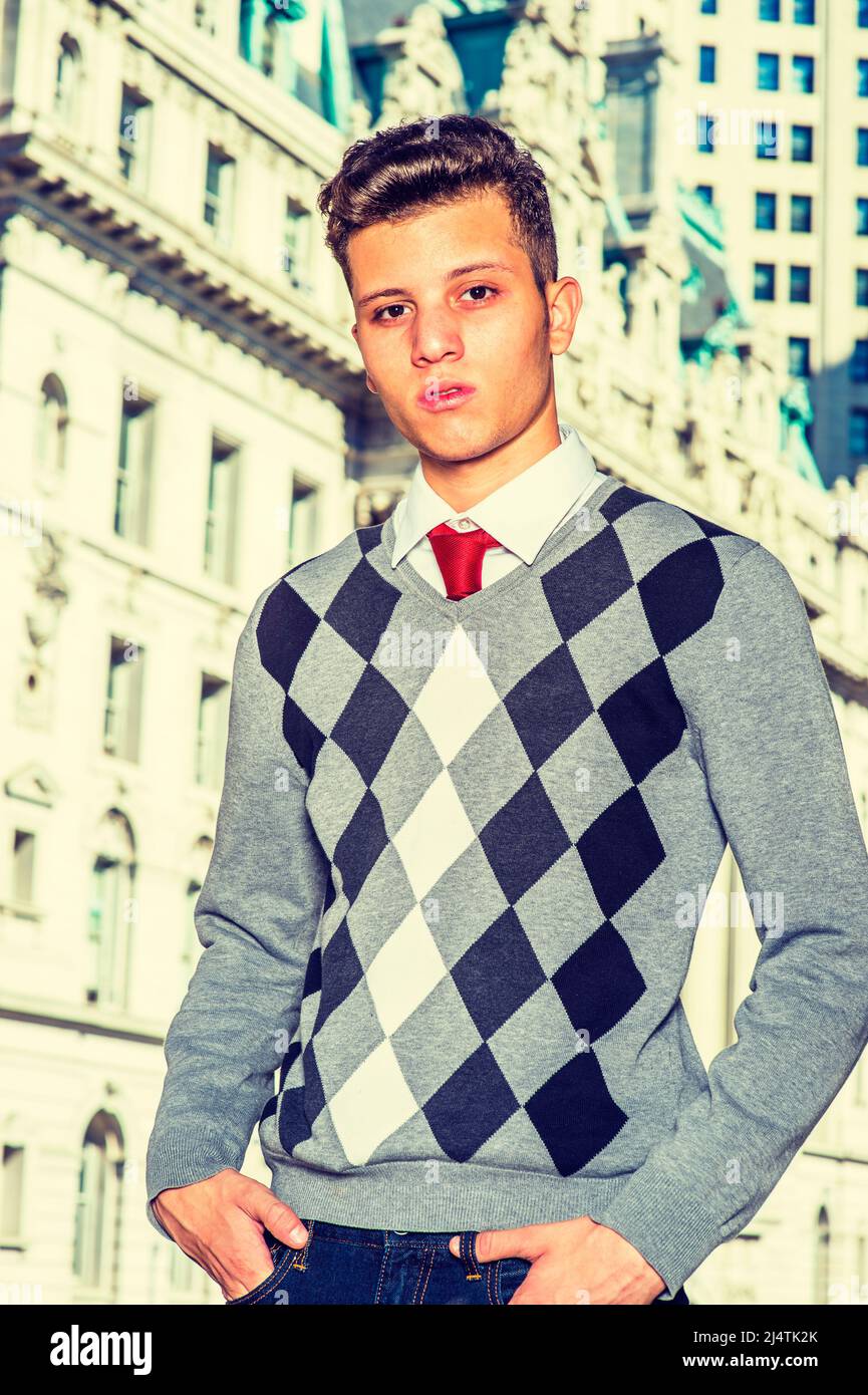 Portrait de l'étudiant de collège. Robe dans un pull à motifs noir, blanc, gris, jeans, mains dans les poches, un jeune homme d'affaires charmant est présent Banque D'Images
