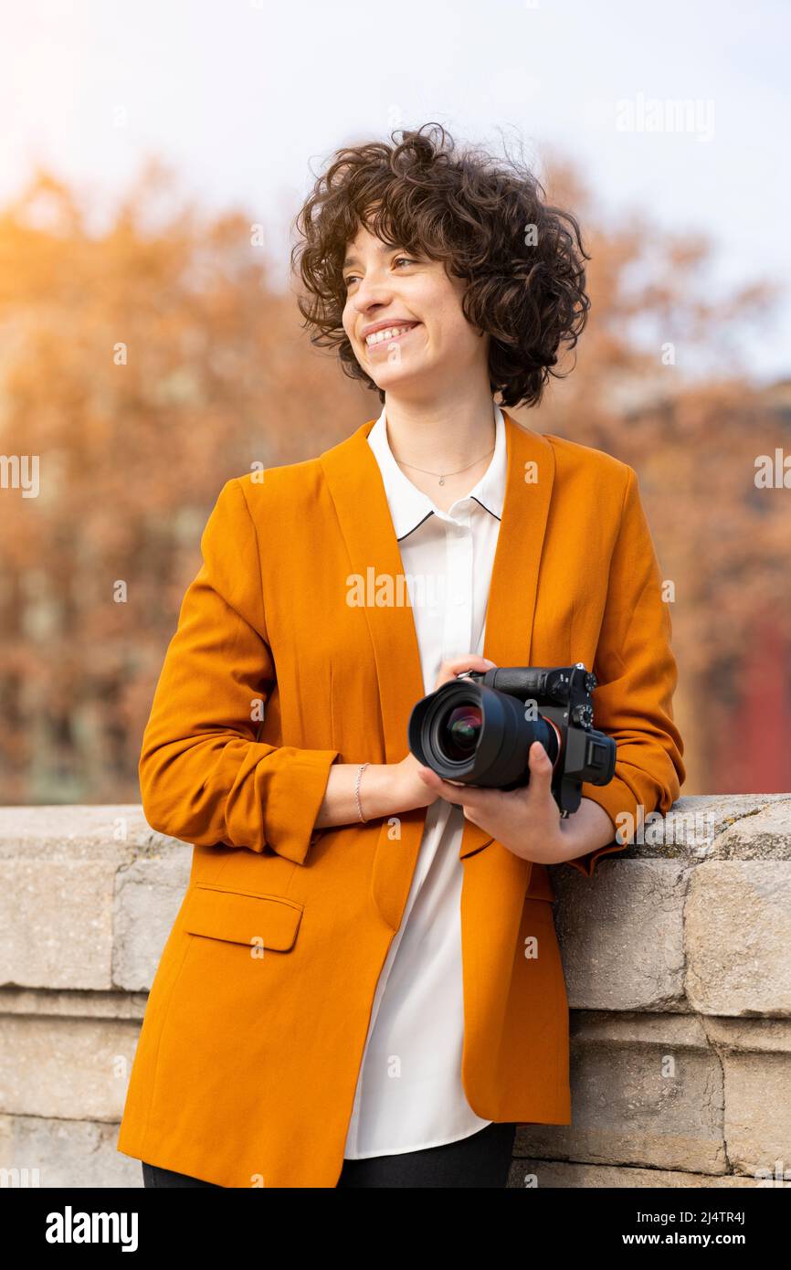 Jeune femme brune aux cheveux bouclés posant avec son appareil photo Banque D'Images