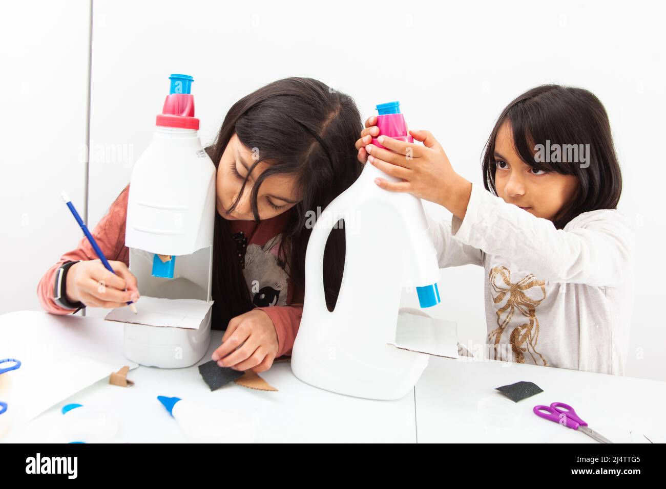 Deux jeunes filles faisant un microscope jouet avec des matériaux recyclables Banque D'Images