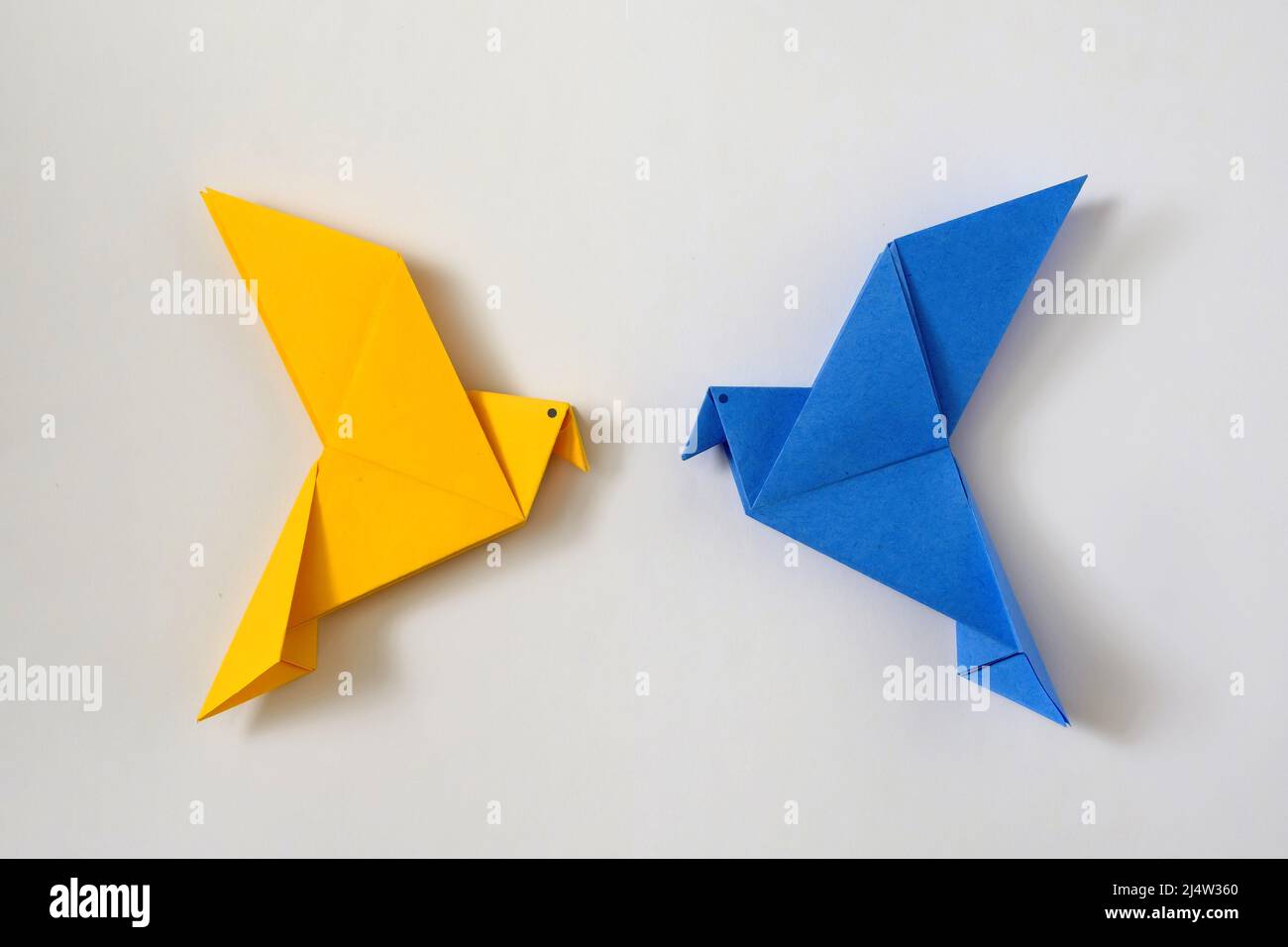 Deux colombes de la paix comme la couleur du drapeau ukrainien. Concept minimal de crise politique nationale du monde de l'aide et du soutien. Jouet origami. Banque D'Images
