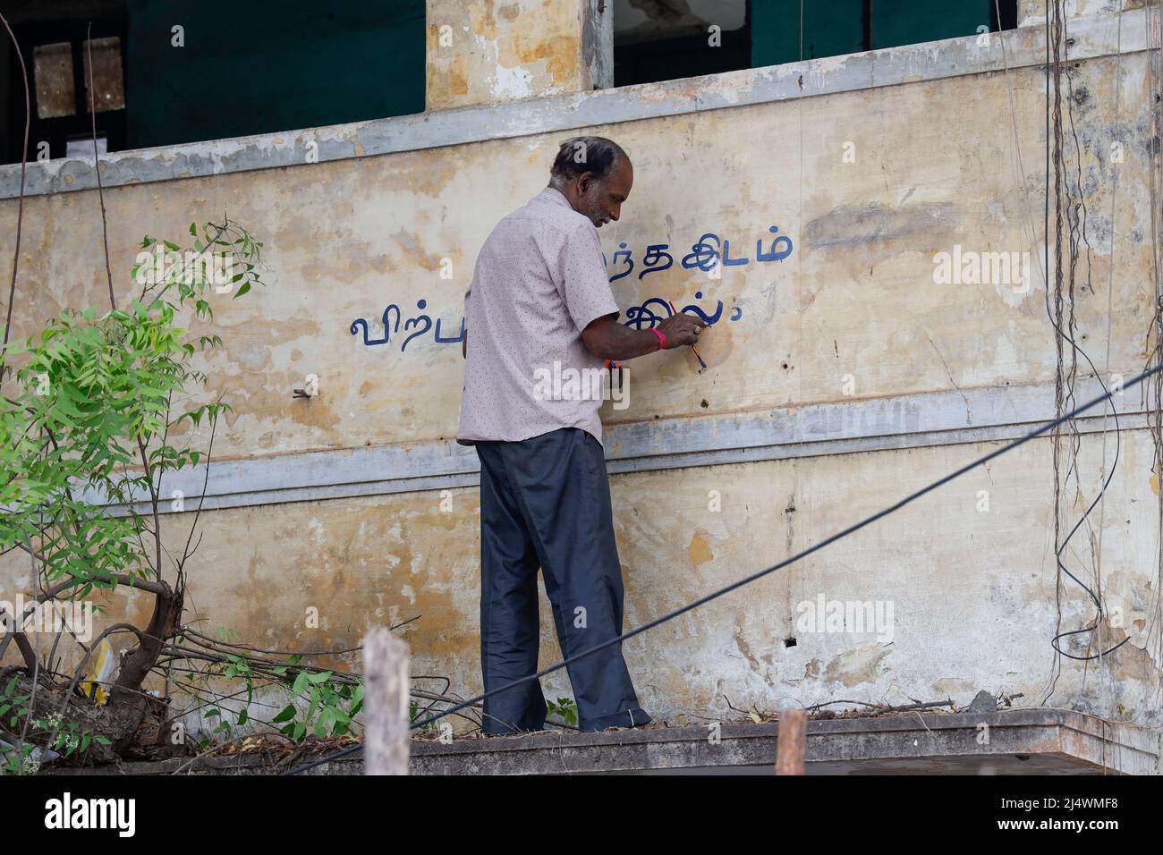 Homme peint un panneau non destiné à la vente sur la façade d'une maison en ruine à Trichy, Tamil Nadu, Inde Banque D'Images