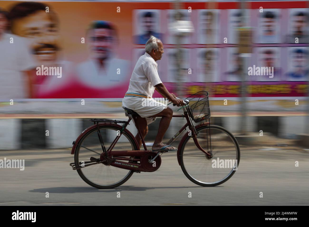 Un vieil homme qui passe devant un mur couvert par les affiches de campagne électorale Trichy, Tamil Nadu, Inde Banque D'Images