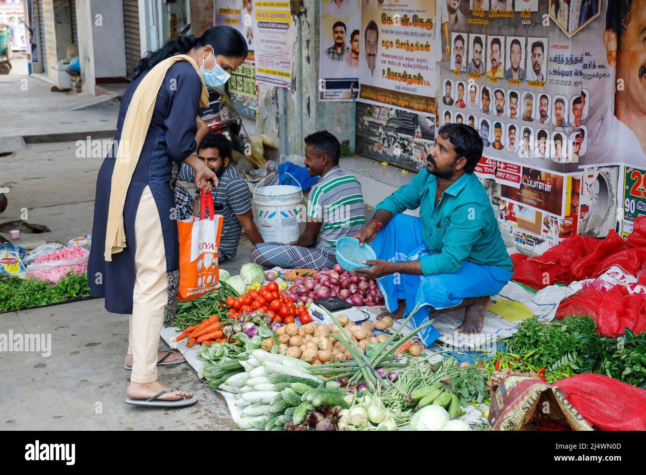 Homme assis sur le trottoir vendant des légumes à Trichy, Tamil Nadu, Inde Banque D'Images