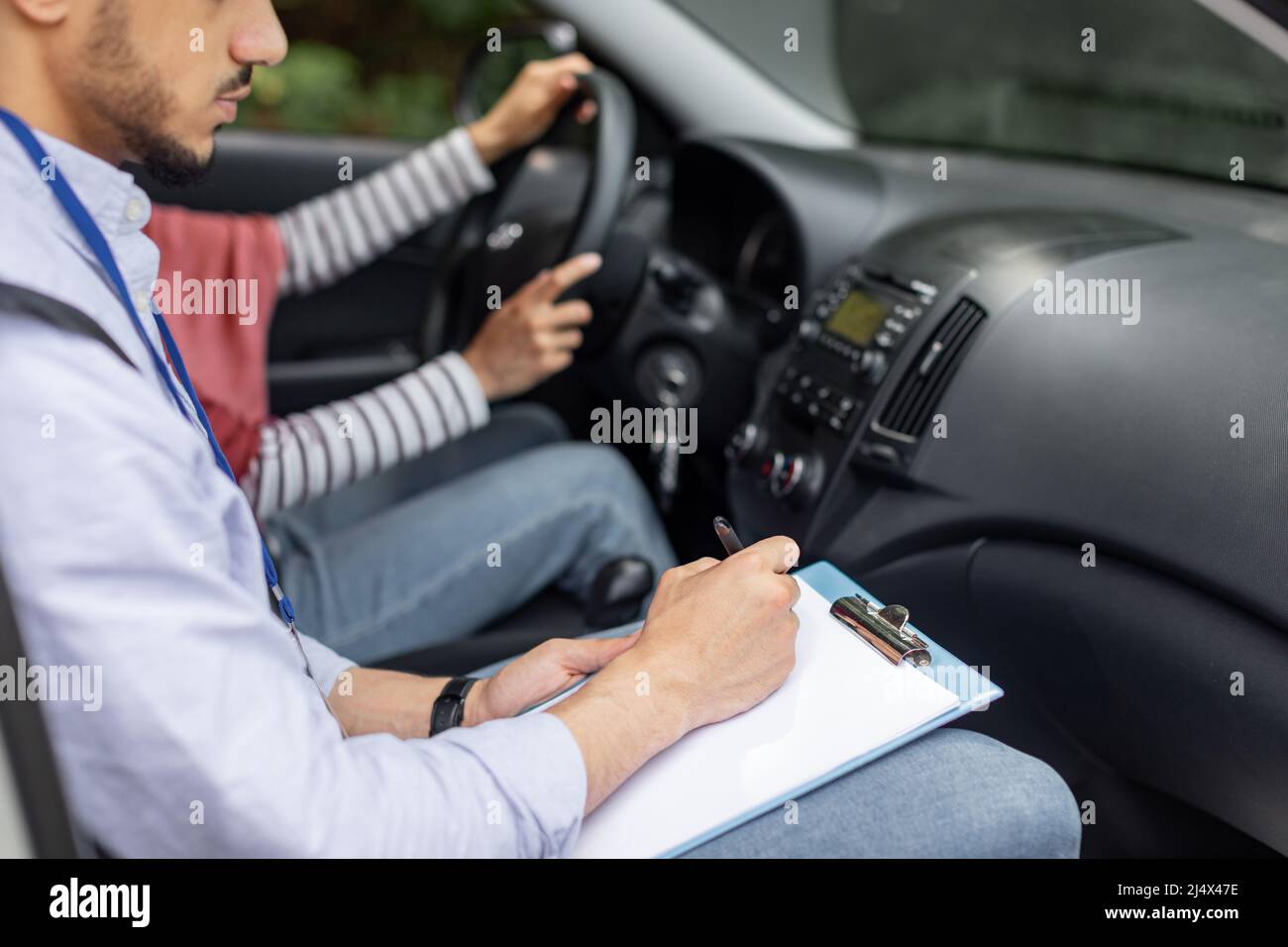 Jeune musulman sérieux, un professeur faisant un essai de conduite d'une femme dans le hijab au volant de la voiture, court Banque D'Images