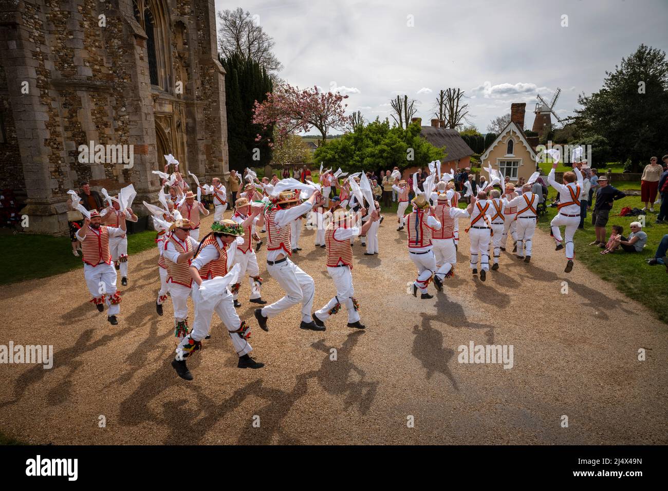 Lundi de Pâques Morris Dancing Thaxted Essex, Royaume-Uni. 18th avril 2022. À la fin du printemps, par temps chaud, les danseuses de Morris Thaxted en rouge et blanc, en visitant les danseurs de Dyke Morris en marron et en blanc du sud du Cambridgshire, effectuent des danses traditionnelles de dMorris dans le triage de l'église de Thaxted avec les maisons d'alms Thaxted et le moulin de John Webb en arrière-plan. Crédit : BRIAN HARRIS/Alay Live News Banque D'Images