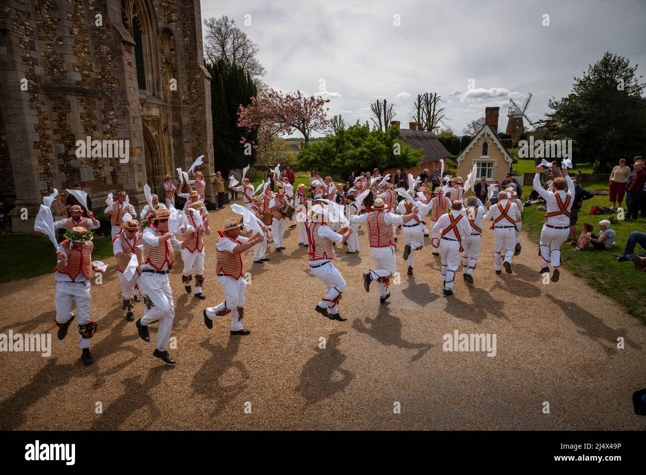 Lundi de Pâques Morris Dancing Thaxted Essex, Royaume-Uni. 18th avril 2022. À la fin du printemps, par temps chaud, les danseuses de Morris Thaxted en rouge et blanc, en visitant les danseurs de Dyke Morris en marron et en blanc du sud du Cambridgshire, effectuent des danses traditionnelles de dMorris dans le triage de l'église de Thaxted avec les maisons d'alms Thaxted et le moulin de John Webb en arrière-plan. Crédit : BRIAN HARRIS/Alay Live News Banque D'Images