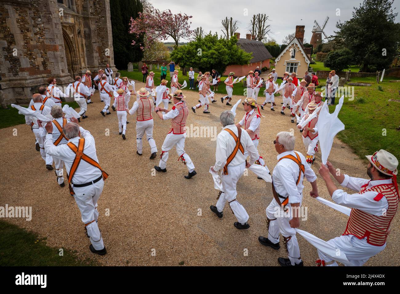 Lundi de Pâques Morris Dancing Thaxted Essex, Royaume-Uni. 18th avril 2022. À la fin du printemps, par temps chaud, les danseuses de Morris Thaxted en rouge et blanc, en visitant les danseurs de Dyke Morris en marron et en blanc du sud du Cambridgshire, effectuent des danses traditionnelles de dMorris dans le triage de l'église de Thaxted avec les maisons d'alms Thaxted et le moulin de John Webb en arrière-plan. Crédit : BRIAN HARRIS/Alay Live News Banque D'Images