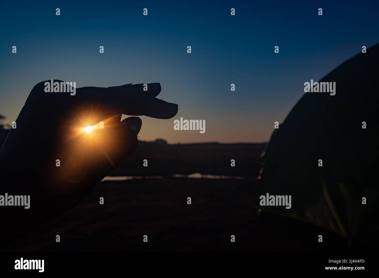 main rétro-éclairée avec faisceau de lever de soleil traversant le trou le matin à partir d'un angle plat Banque D'Images