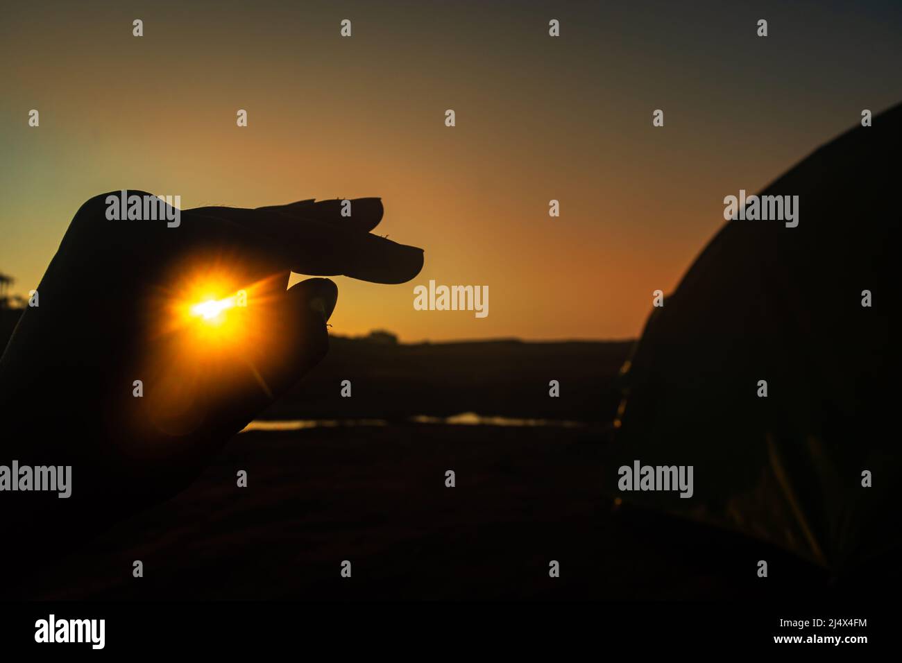 main rétro-éclairée avec faisceau de lever de soleil traversant le trou le matin à partir d'un angle plat Banque D'Images