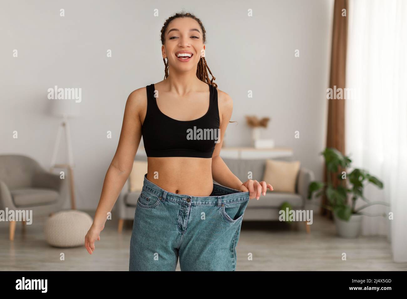 Happy Fit Afro-américaine femme portant de vieux grands jeans en intérieur Banque D'Images