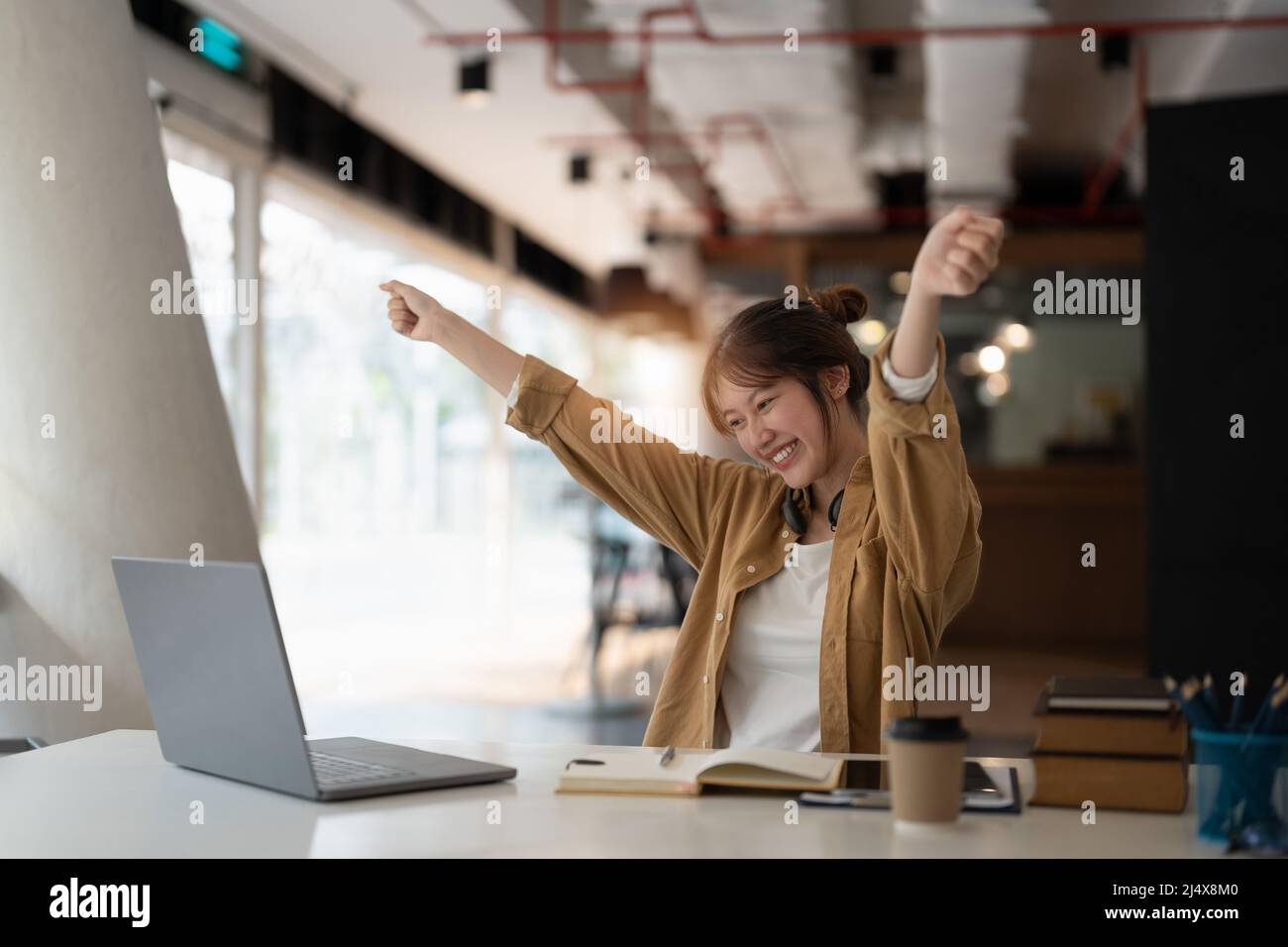 Un jeune étudiant asiatique heureux se lève avec enthousiasme lors de l'enseignement à distance à domicile Banque D'Images