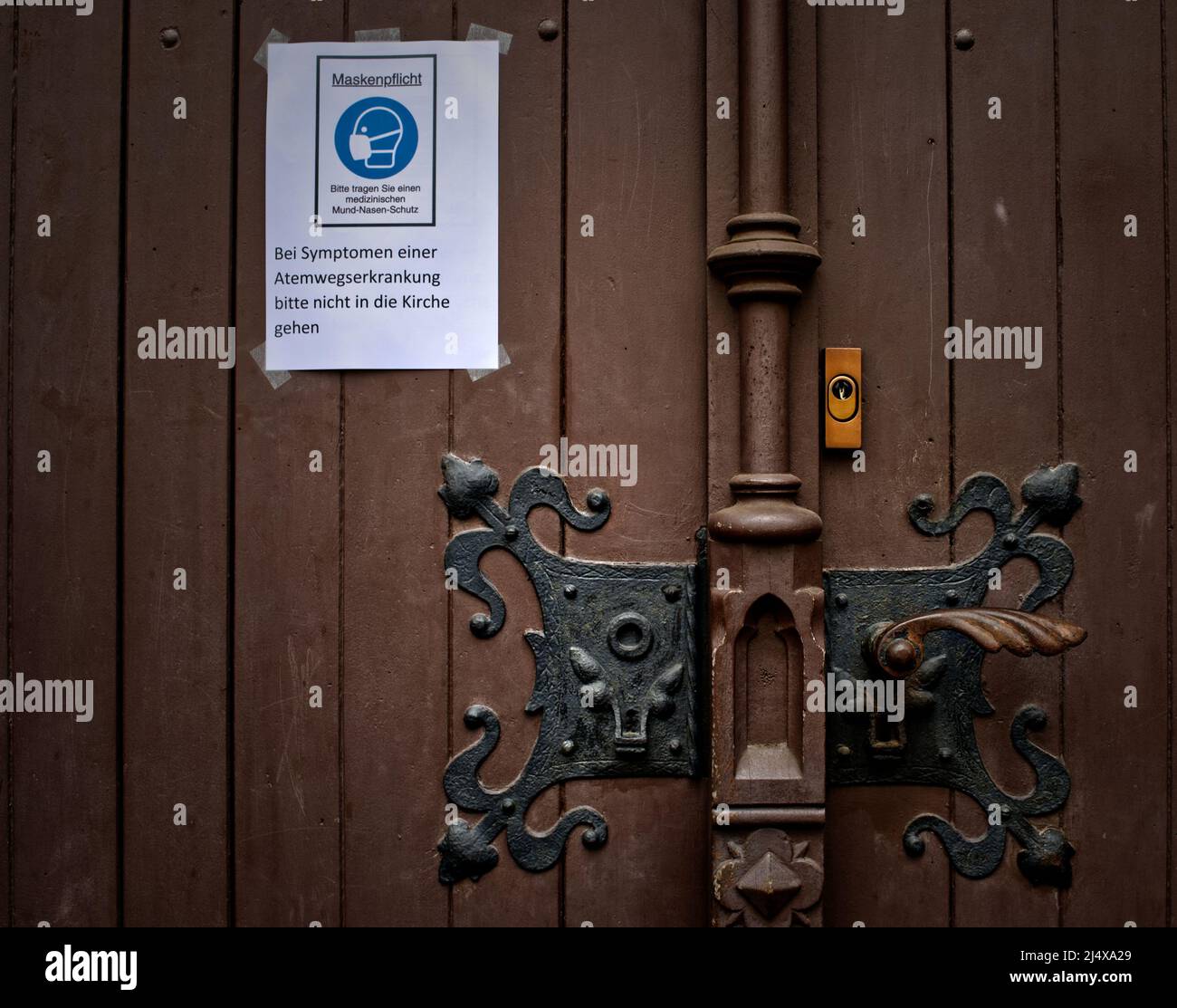 Signe pour les masques faciaux obligatoires et un avertissement de ne pas visiter l'église en cas de symptômes d'une maladie des voies respiratoires sur une porte en bois marron lourde (en Allemagne) Banque D'Images Signe pour les masques faciaux obligatoires et un avertissement de ne pas visiter l'église en cas de symptômes d'une maladie des voies respiratoires sur une porte en bois marron lourde (en Allemagne) Banque D'Images