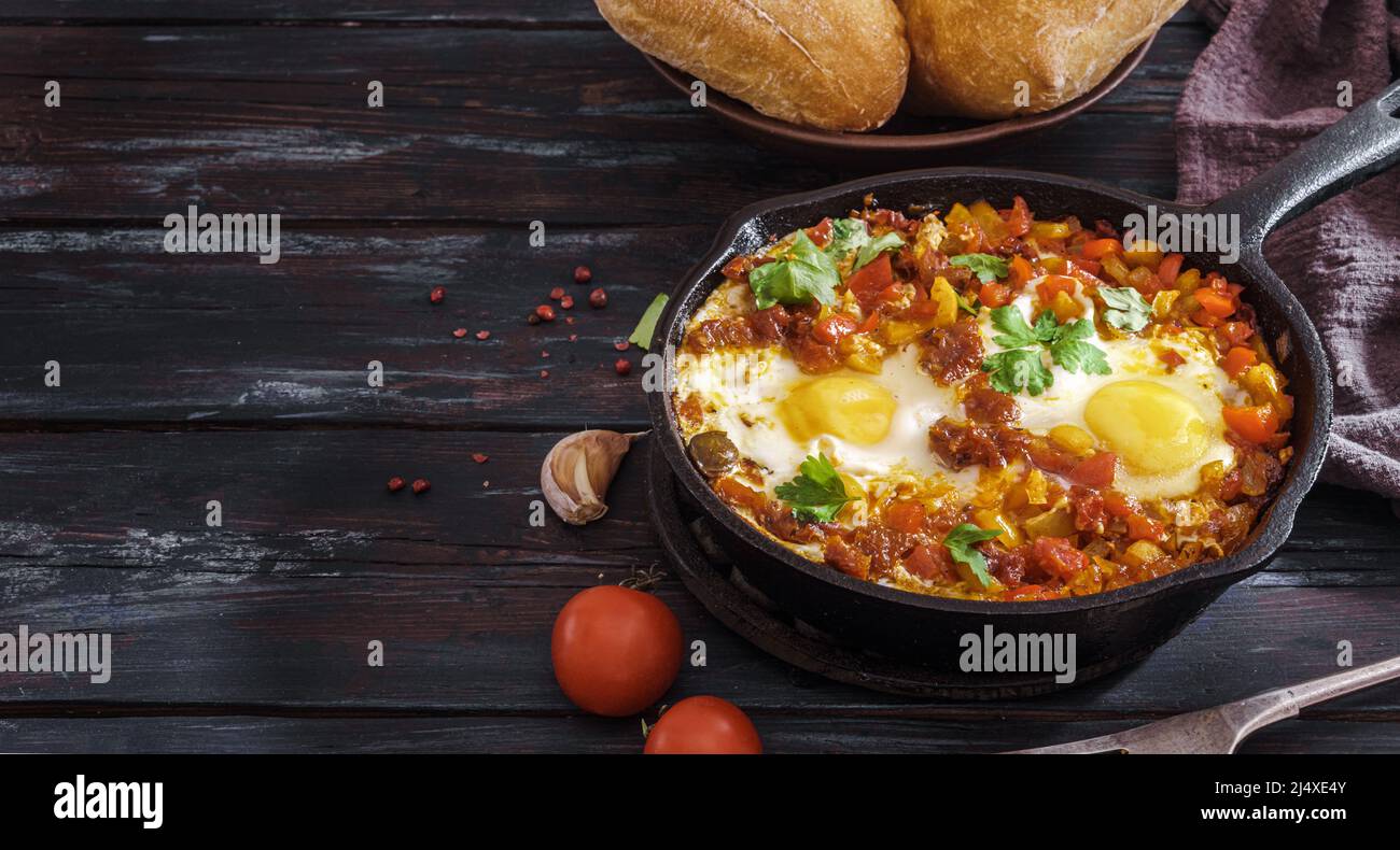 Œufs frits sur une casserole avec petits pains et espace de copie. Shakshouka est un plat maghrébine d'œufs pochés dans une sauce de tomates, d'huile d'olive, de poivrons, d'oignons et d'ail Banque D'Images