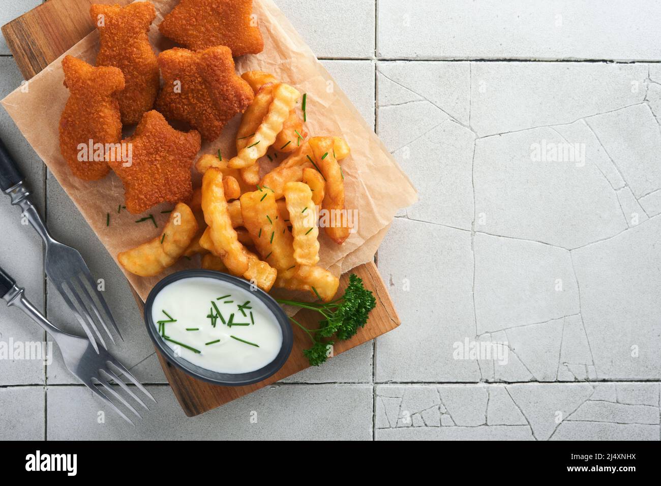 Fish Chips, restauration rapide britannique. Les bâtonnets de poisson aux frites sont fixés sur un panneau rustique, sur un fond de table de comptoir en carreaux gris craquelés. Tradition Banque D'Images