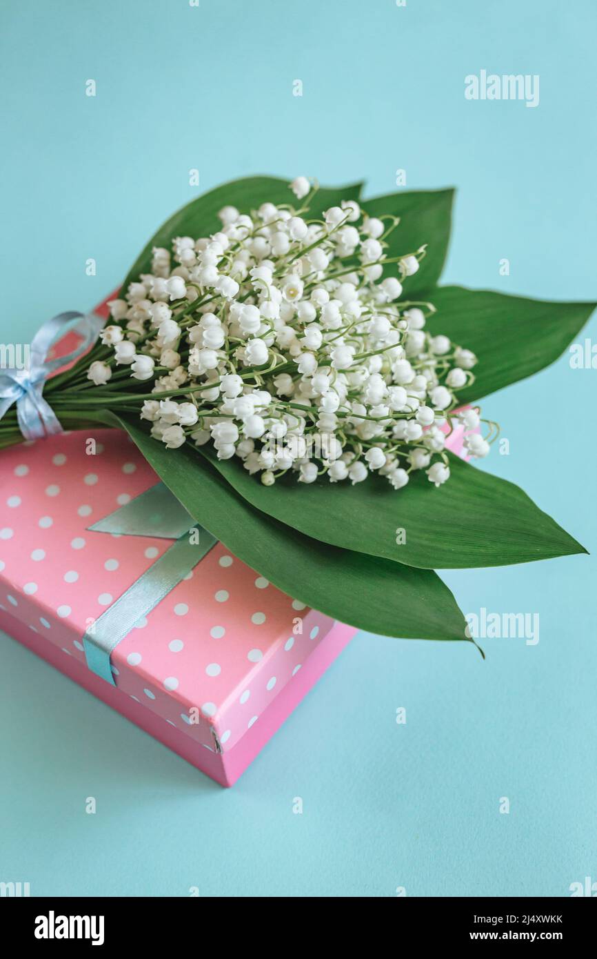 Bouquet de Lily de la vallée fleurs et cadeau sur fond bleu. Banque D'Images