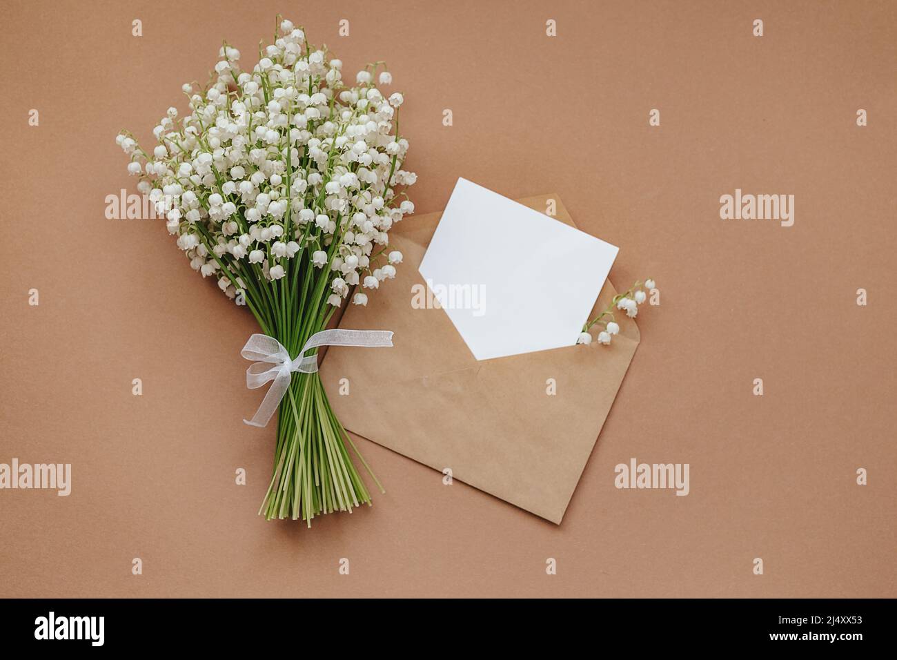 Lily de la vallée et papier vide avec espace de texte sur fond beige Banque D'Images